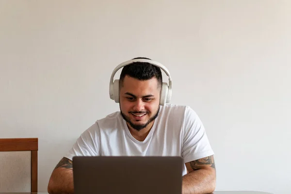 Laptop ve kulaklık kullanan Latin bir gencin ön görüntüsü