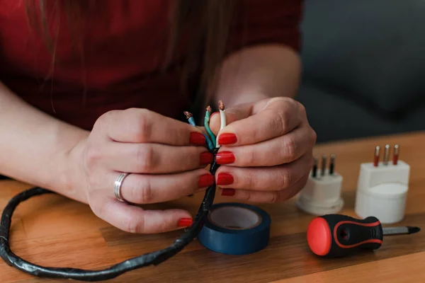 Bir kadının ellerinin kabloyu tamir edişinin ön görüntüsü.
