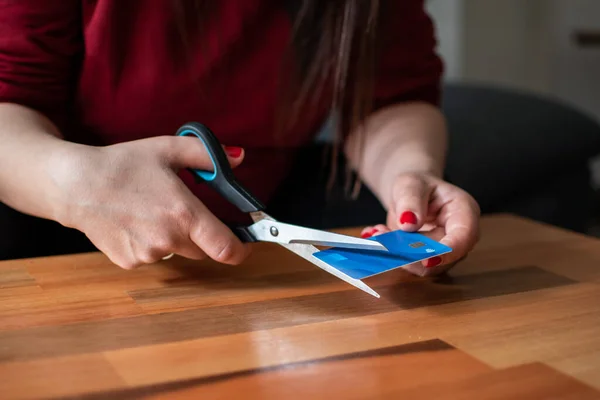 unrecognizable woman cutting a credit card in half with scissors