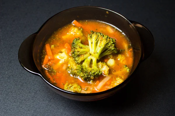 Plate with soup on a black background. Broccoli soup. Delicious food. Background.