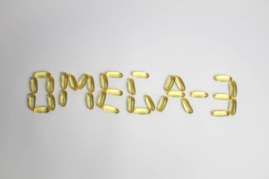 OMEGA-3 kapsülleri beyaz arkaplanda balık olduğunu söylüyor 