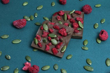 Kare şeklinde çikolatalar, kurutulmuş ahududu ve balkabağı çekirdekli. Üst görünüm.