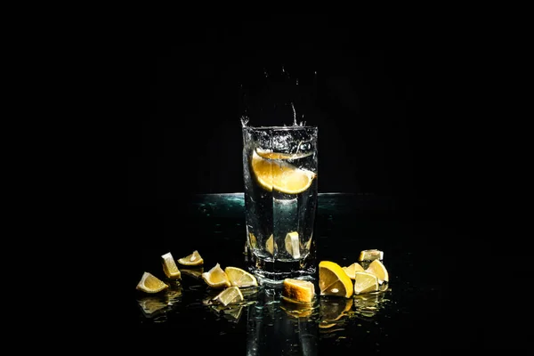 Uma Fatia Limão Cai Copo Fundo Preto Gotas Água Voadora — Fotografia de Stock