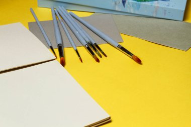 Düz fırça ve defter, kağıtlar.