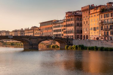 Florence, Italy -20 June, 2019 : view of St Trinity Bridge, river Arno and residential area of the city at golden hour.