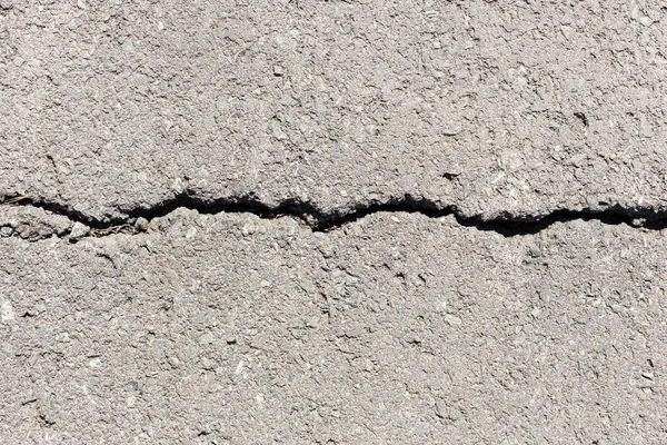 Büyük çatlaklarla aşınmış ve kırılmış asfalt. Çatlaklı eski yol beton dokusu
