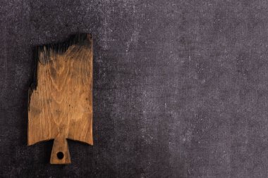 Karanlık bir arka planda eski bir kesme tahtası. Yemek için kesme tahtası. Tahta yanmış. İmza arkaplanı.