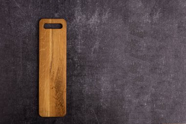 Karanlık bir arka planda uzun bir tahta kesme tahtası. Yemek için kesme tahtası. İmza Arkaplanı