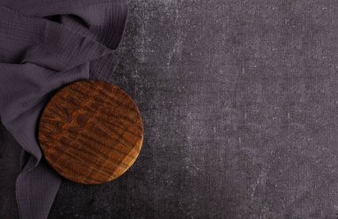 Karanlık arka planda boş vintage kesim tahtası, yiyecek arka planı konsepti. Yuvarlak tahta. Etiketin altına yerleştir. Gri peçete