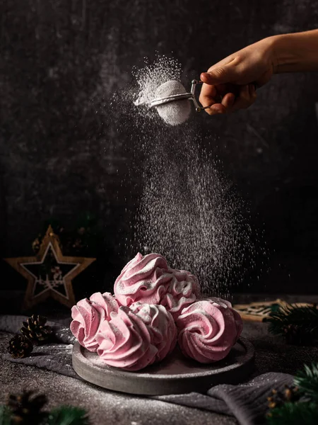 Marshmallow, koyu bir arka planda lokum. Çilek aromalı pembe kabarık lokum. Yeni yıl için tatlılık. Karanlık arka plan. Pudra şekeri serpin. Hareketi dondur.