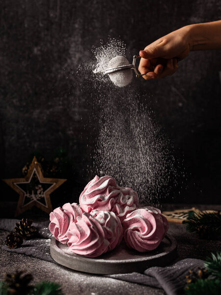 Marshmallow - marshmallow on a dark background. Pink fluffy marshmallow with strawberry flavor. Sweetness for the new year. Dark background. Sprinkle with powdered sugar. Freeze movement.