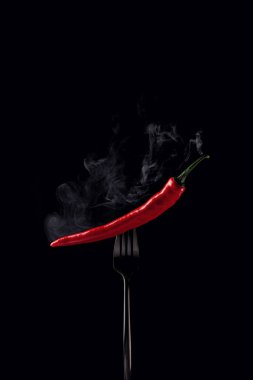 Siyah bir arka planda siyah bir çatalda acı kırmızı biber buharı. Tüttür. Etiket için yer