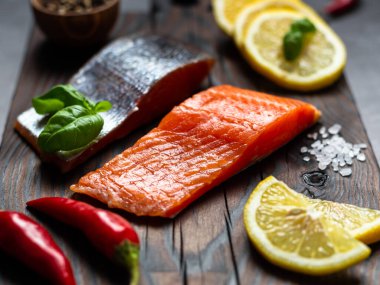 Somon balığı. Çiğ alabalık ve kırmızı balık bifteği ahşap bir tahtanın üzerinde otlar, limon ve zeytinyağı ile servis edilir. Somon balığı ve deniz ürünleri hazırlığı. Sağlıklı Yeme Konsepti