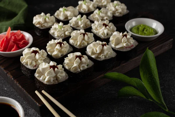 Somonlu suşi, füme yılan balığı, avokado, siyah arka planda krem peynir. Suşi menüsü. Japon yemeği. Yeşil keten peçete
