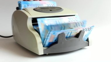 Elektronik para sayacı faturaları sayar. Banknotların değeri iki bin ruble. Video sayacı ruble sayıyor. Rubleleri daktilo sayar.