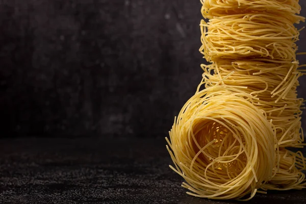 Kapellini spagettisi. Koyu bir yapısal arka plan. Kopyalanacak yer de var. Kuleye istiflenmiş spagetti. Kopyalama alanı