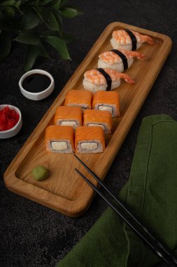 Suşi ruloları, maki, nigiri, siyah arka planda tahta bir tahtada servis edilir, boşluğu kopyala