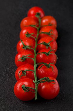 Kırmızı vişneli domates grubu siyah beton arka planda yakın plan