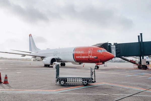 Kopenhag, Danimarka - 30 Ocak 2019. Kopenhag Kastrup Havaalanı 'na park etmiş Norveçli (Anders Zorn ahır) Boeing 737-800 uçağının yanında boş bir bagaj arabası. Avrupa düşük maliyetli şirketi.