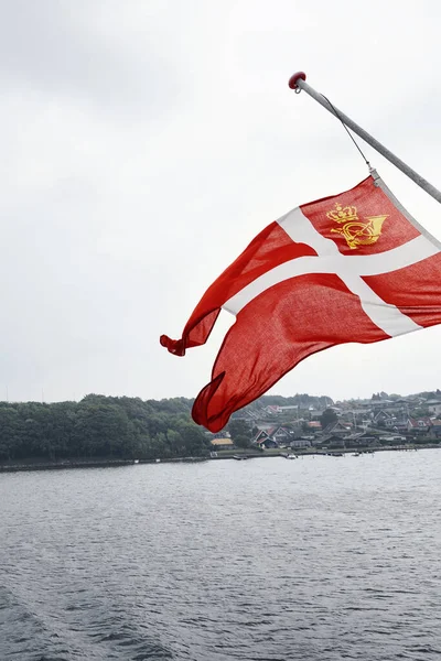 Svendborg, Danimarka - 14 Ağustos 2018. Büyük bir Danimarka bayrağı taşıyan bir feribot Svendborg limanına varır..