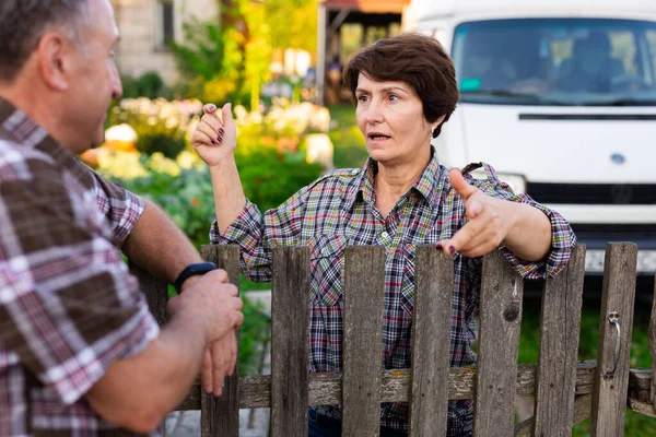 neighbors man and woman chatting near the fence in the village