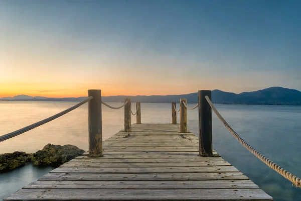 Drewniany most przeciwko zachody słońca i morskie w Oropos w Grecji. — Zdjęcie stockowe