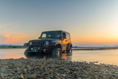 Athens, Greece 1 July 2016. Jeep 4x4 against the sunset. Jeep got stuck in the mud. clipart