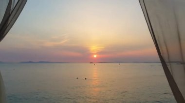 Gün batımı manzarası ufuktaki bir sahilde bir perdenin ardında.. 