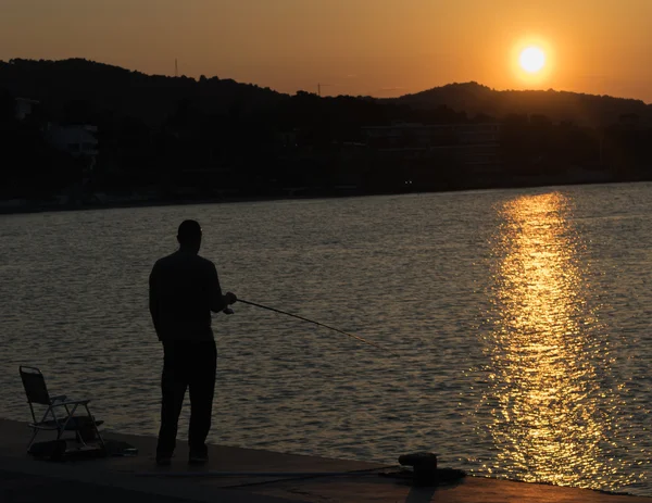 Fisherman chilling out against the beautiful sunset in Greece. Royalty Free Stock Images
