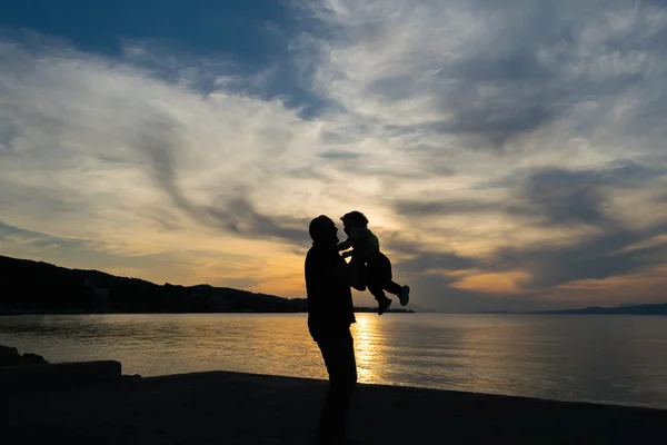 Father and son love silhouette against a dramatic sky.