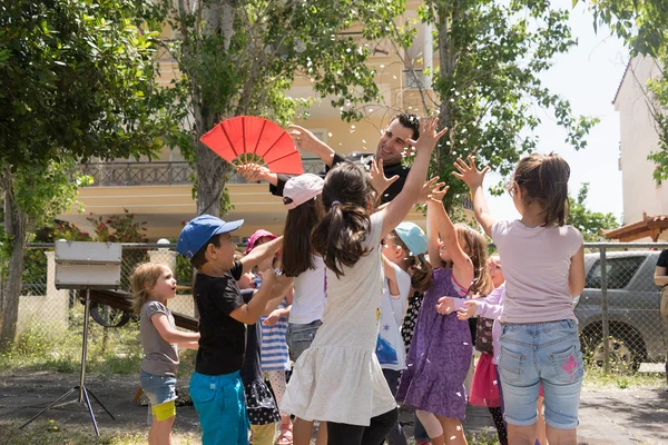 Date: 17-5-2015. Location: Park in Athens. Magic show with Tristan. Happy kids trying to catch confetti. — Stock Fotó