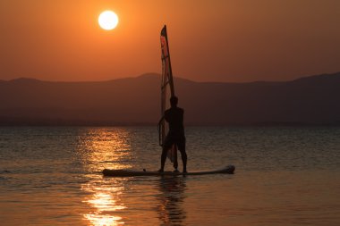 Sörf adam siluet yine güzel bir gün batımı arka plan olarak.