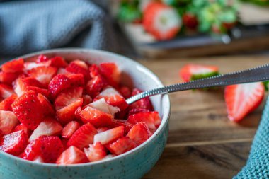 Ahşap kırsal masada bir kase taze kesilmiş çilek. Arka planda bulanıklık olan yakın görüntü. Seçici odak