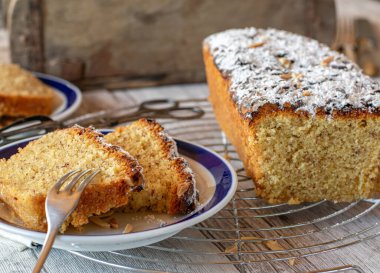 Evde, tabakta servis edilen kırsal bir mutfak masasında bademli nefis bir kek. 