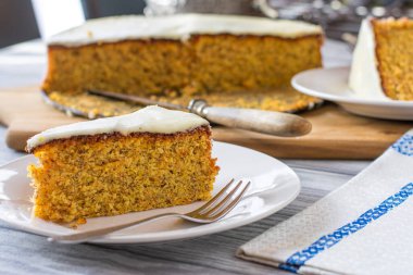 Bir parça taze fırında havuçlu kek badem ve limonlu kadırga ve arka planda pastayla servis edilen köy mutfağı masasında. 
