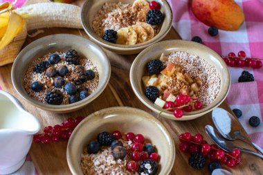 Yukardan gelen kırsal ve doğal taş kaplarda sunulan meyve ve meyveli mısır gevreği çeşitleriyle kahvaltı masası.