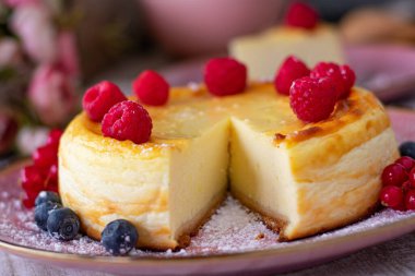 Geleneksel Alman peynirli keki ya da quarkkuchen soluk pembe tabakta taze ahududu ile servis edilir.