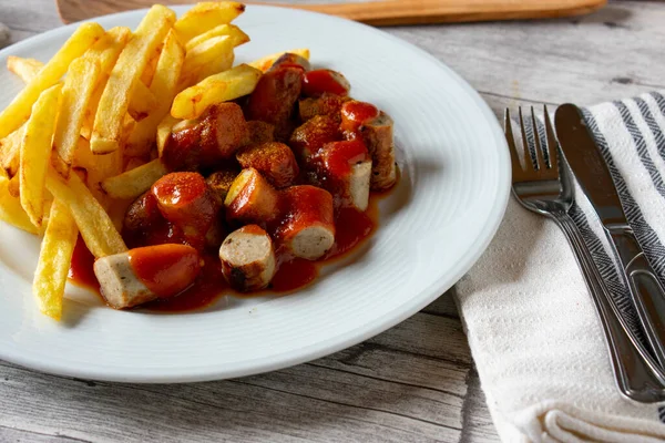 自制的新鲜咖喱饭配薯条 德国传统的快餐餐放在盘子里 刀叉放在乡村木桌的背景上 — 图库照片