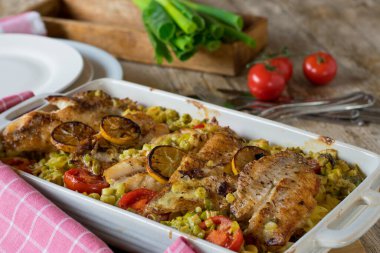 Kırmızı balık filetosu, sebze ve lezzetli ve kremalı beşamel soslu makarnadan yapılmış balık güveci. Mutfak masasının arka planında beyaz bir fırın tabağında servis edilmiş.