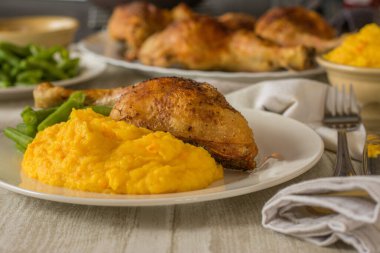 Roasted Chicken legs with potatoe pumpkin puree served with green beans on a plate on dinner table background. 