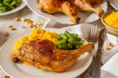 Roasted Chicken legs with potatoe pumpkin puree served with green beans on a plate on dinner table background. 