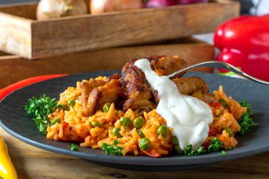 Pan fried low fat pork meat served with mediterranean vegetable rice and yogurt sauce on a plate