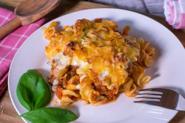 Makarna güveci alla bolonez fussili erişte, bolonez sosu, bechamel sosu ve üstüne de mutfaktaki beyaz tabakta servis edilen gouda ve mozzarella peyniri karışımı.