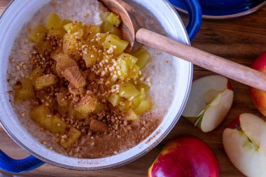 Taze pişmiş yulaf lapası. Yanında sotelenmiş elma, kavrulmuş fındık ve tarçın var. Genel ve izole görünüm