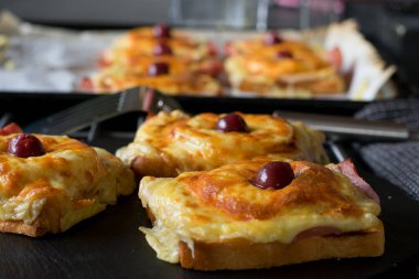 Jambon ve peynirli tost, ananas ve neşeyle kaplanmış ve mutfak masasında servis edilmiş.