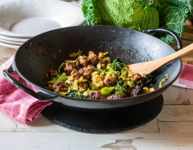 Baharatlı köfteli taze Wok yemeği ve sade bir masa arkasında servis edilen baharatlı lahana malzemeleri, tabaklar. yakın plan görünümü