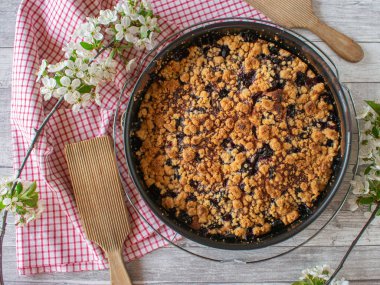 Ekşi kirazlarla yapılmış taze bir vişneli turtanın tepeden görünüşü ve kırsal, ahşap masa arka planında bahar mevsimi tavasında sıcak servis edilmesi. Kopyalama alanı ile yakın ve izole görünüm