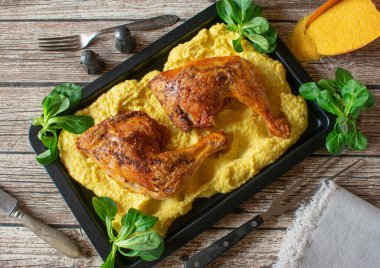 Kızarmış tavuk budu ve polenta yukarıdaki kırsal masa arka planında servis edilir.