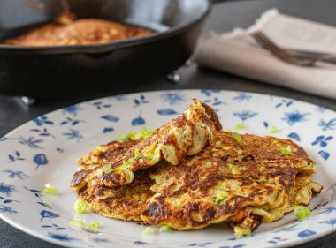 Kabartılmış amaranth, yumurta, soğan ve rendelenmiş kabak ile yapılan sağlıklı ve glütensiz krepler kırsal dökme demir bir tavada kızartılmış ve bir tabakta servis ediliyor. Yakın görünüm