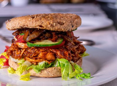 Lezzetli ve ev yapımı et, barbekü sosu, salata ve tabakta karamelize edilmiş kırmızı soğanlı hamburger. Bulanık tablo arkaplan ile yakın plan ve ön görünüm